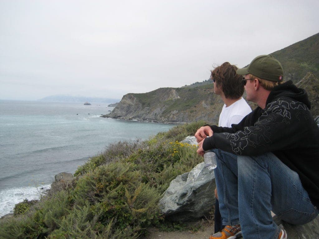 Surfers sitting on cliff